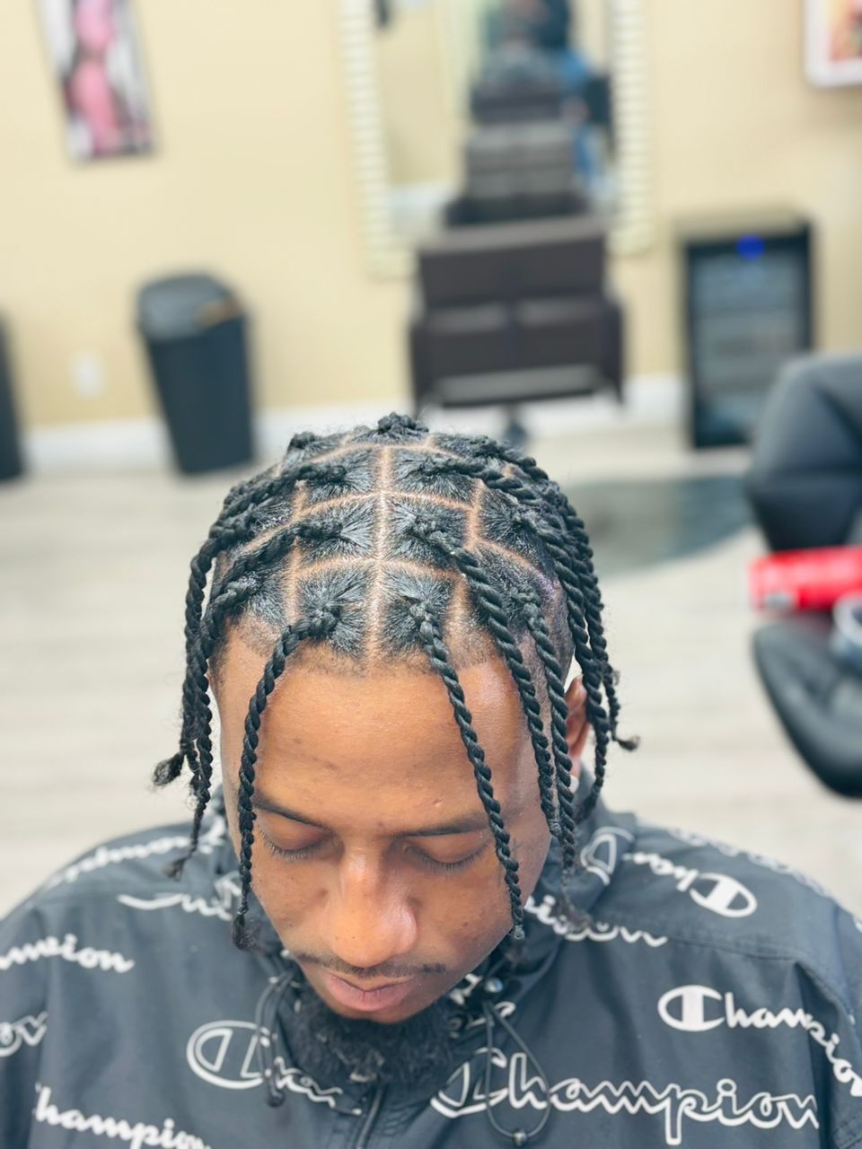 Person with detailed twisted braids and geometric hair design wearing Champion shirt